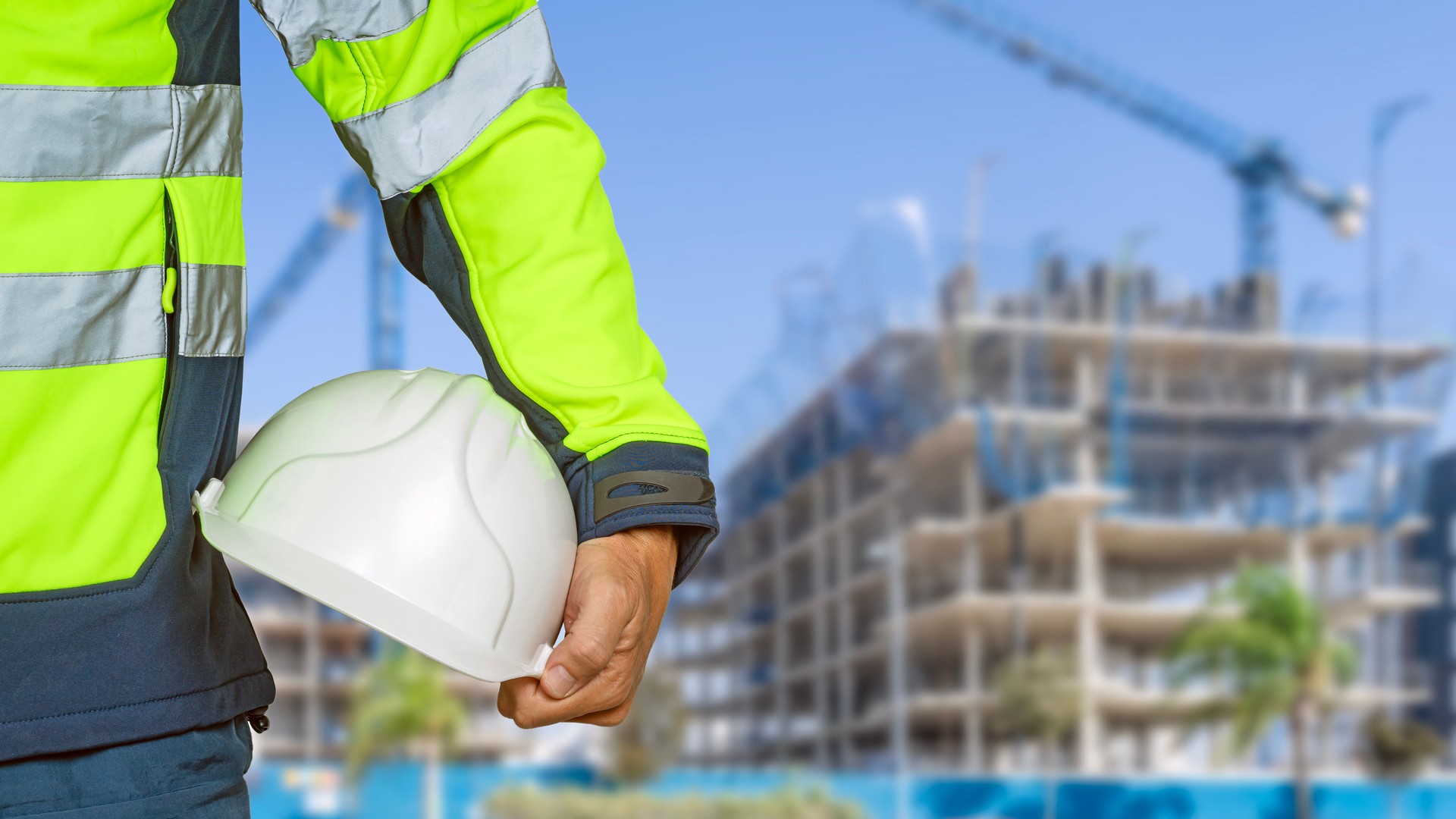 Construction worker holding safety hard hat in a building under construction.